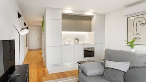A modern kitchen with white cabinets, a built-in oven, and a coffee maker. - GuestReady - Trendy getaway in the heart of Porto (Porto)