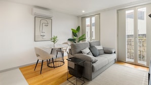 A modern living room with a grey sofa, a round table, and a potted plant. - GuestReady - Trendy getaway in the heart of Porto (Porto)