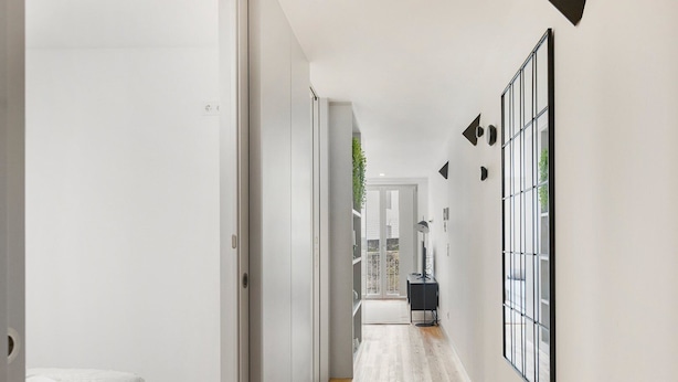 A modern hallway with a bed, a black floor lamp, and a view of the outdoors. - GuestReady - Trendy getaway in the heart of Porto (Porto)