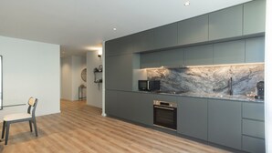 Una cocina moderna con armarios grises, un salpicadero de mármol y un horno empotrado.