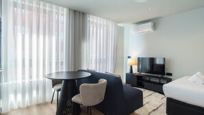 A modern hotel room with a round table, two chairs, a sofa, a TV, and a bed. - GuestReady - Trendy Studio Gaia (Vila Nova de Gaia)