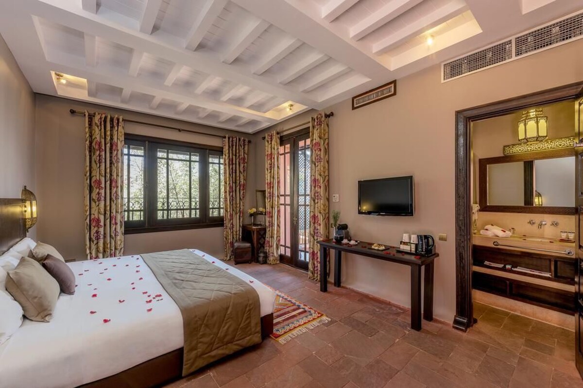 A hotel room with a bed, a TV, a desk, and a bathroom.