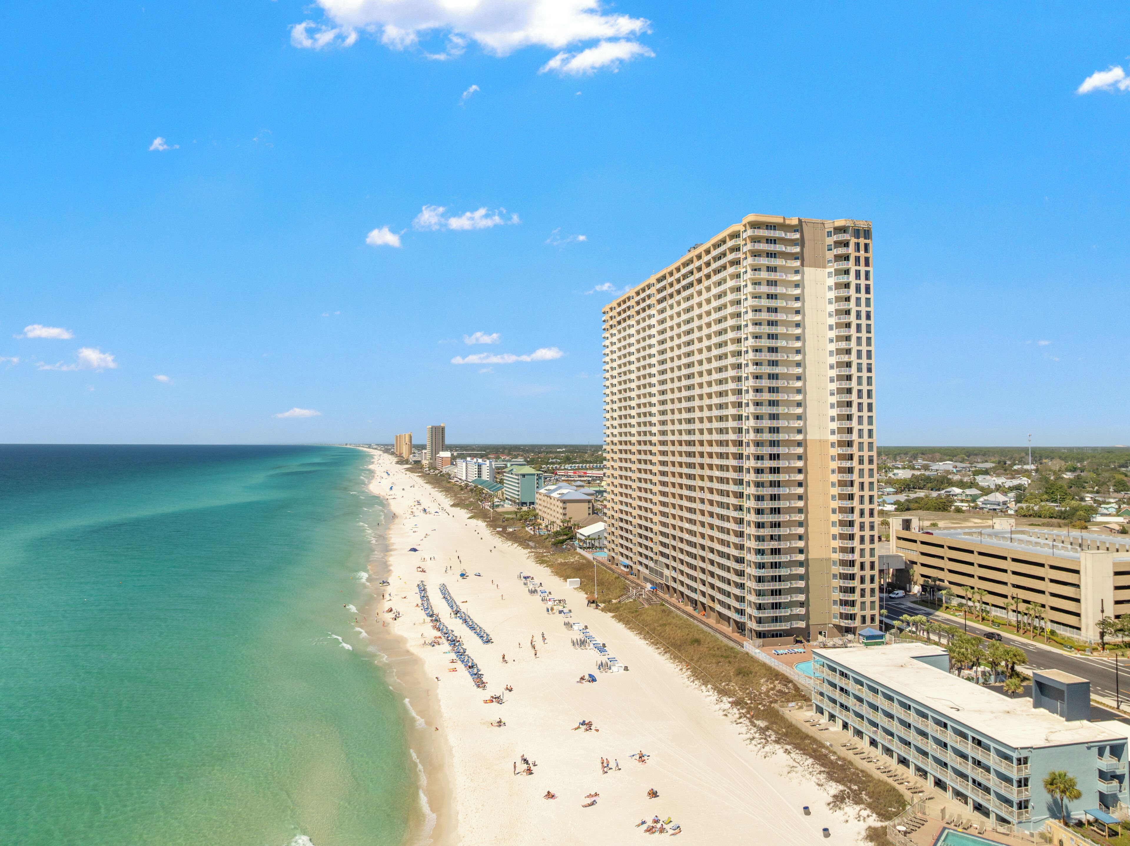 A coastal hotel with a beach view, multiple floors, and a parking structure.