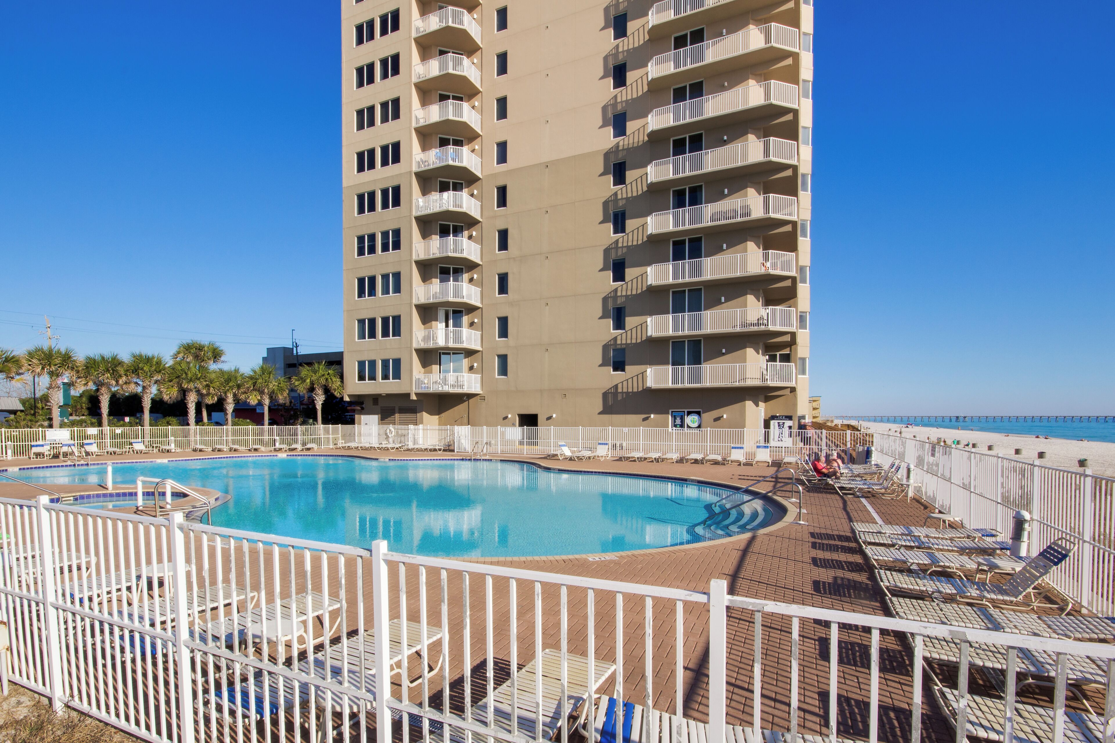 A swimming pool with lounge chairs and a high-rise building in the background.