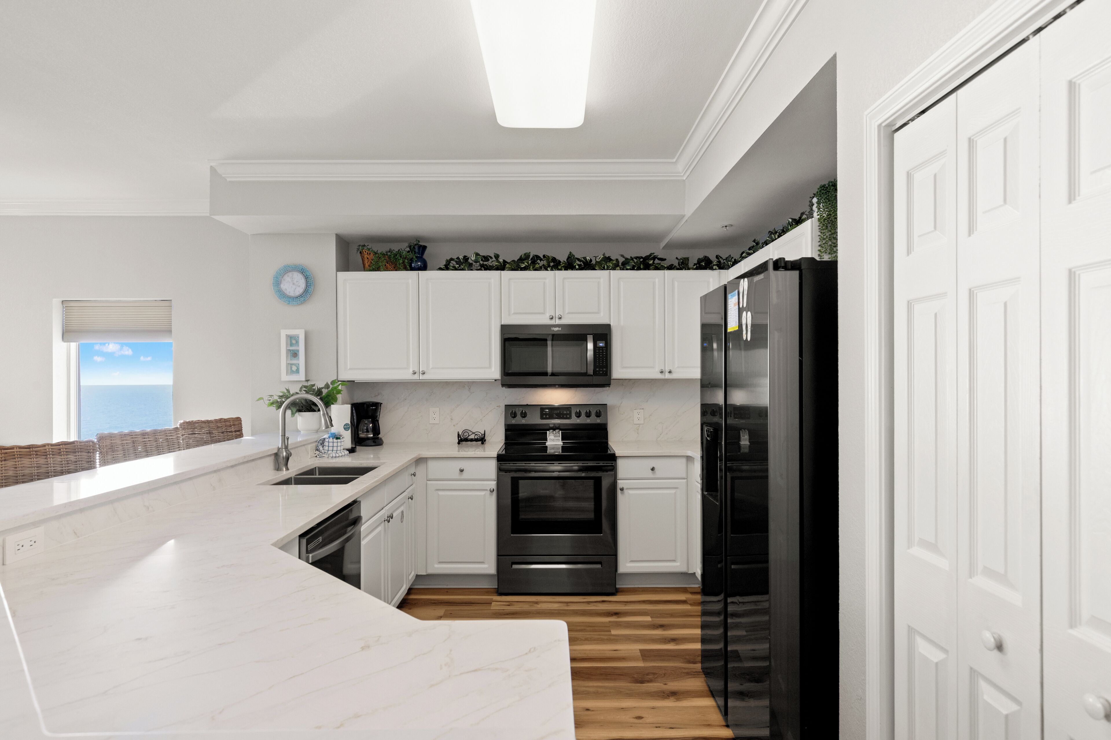Eine moderne Küche mit weißen Schränken, einem schwarzen Kühlschrank und einem eingebauten Backofen.