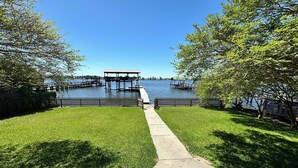 A pathway leading to a dock over water, surrounded by grass and trees.