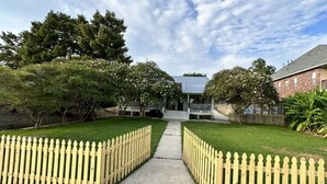 A pathway leading to a building with a white picket fence on both sides.