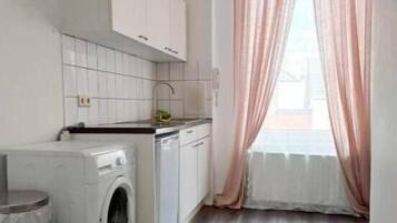 A compact kitchen with a washing machine, a sink, and cabinets.