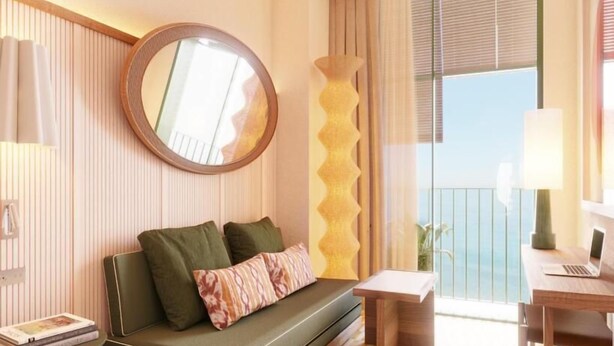 Une chambre d’hôtel avec un canapé, une petite table, un ordinateur portable et une vue sur l’extérieur.