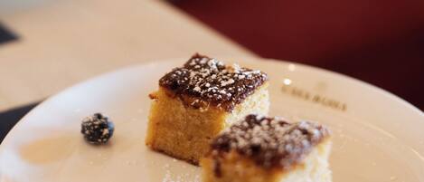 A dessert plate with two square pieces of cake and blueberries on a white plate.