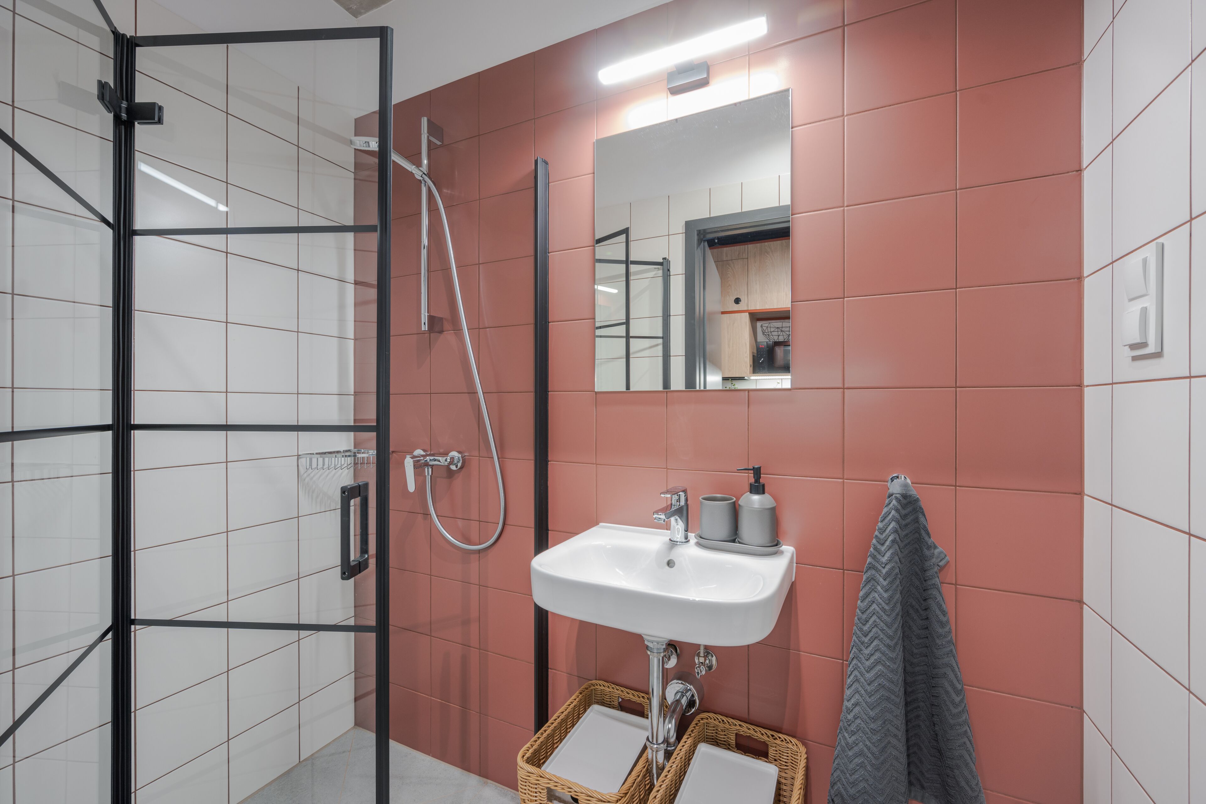 Une salle de bain avec une douche à parois de verre, un lavabo blanc avec un miroir au-dessus, et une serviette accrochée au mur.