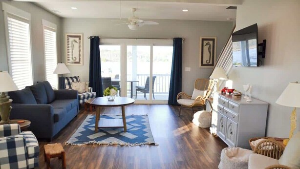 Een woonkamer met een bank, fauteuils, een eettafel en een trap.