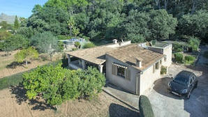 Uma villa com telhado de cerâmica, rodeada por vegetação exuberante e árvores.