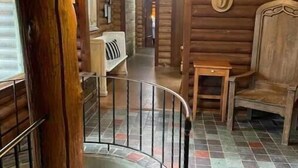 A wooden interior with a spiral staircase, a wooden bench, and a small table.