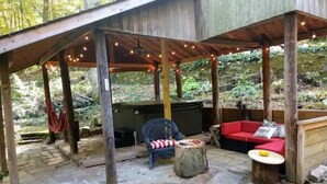 An outdoor patio area with stone flooring, wooden furniture, and string lights.