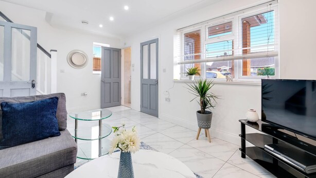 A modern living room with a sofa, TV, glass coffee table, and a potted plant. - 3 Bedroom House with Parking in Windsor (Windsor)
