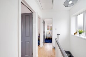 A narrow hallway with a wooden floor, white walls, and a window on the right. - 3 Bedroom House with Parking in Windsor (Windsor)