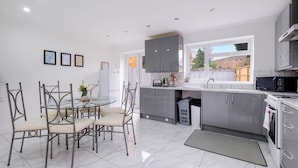 A modern kitchen with grey cabinets, a dining table with chairs, and a large window. - 3 Bedroom House with Parking in Windsor (Windsor)