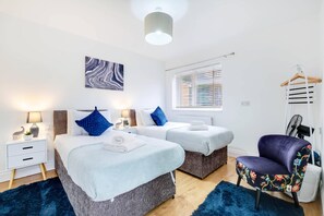A bedroom with two beds, a chair, and a bedside table with a lamp. - 3 Bedroom House with Parking in Windsor (Windsor)