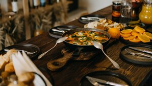 Une table à manger dressée avec différents plats, assiettes et couverts.