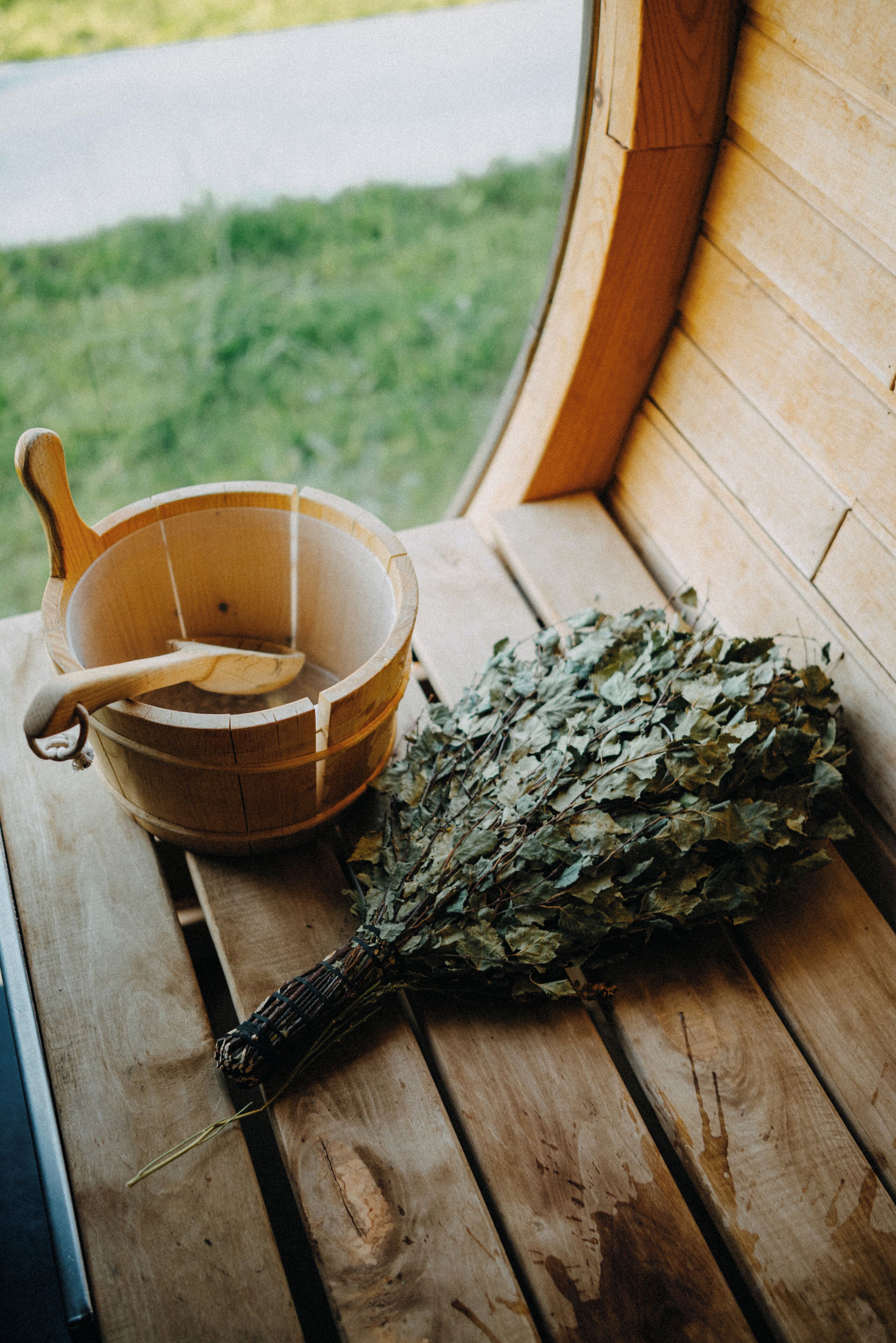A wooden bench with a wooden bowl and a bundle of dried leaves.
