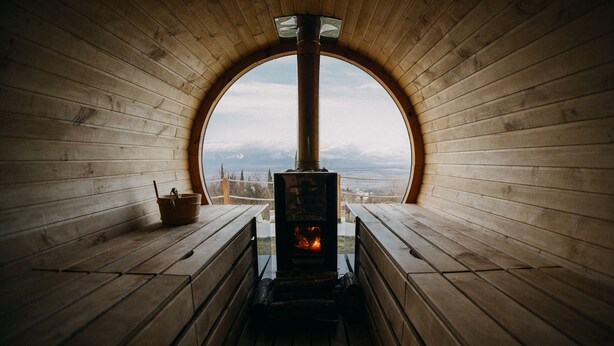 Une cabane en bois dotée d’une fenêtre ronde et d’un poêle à bois.