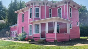 A two-story pink house with a porch and multiple windows.