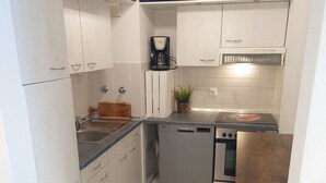 Een kleine keuken met witte kasten, een vaatwasser, een koffiezetapparaat en een broodrooster.