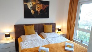 Een hotelkamer met een groot bed, twee nachtkastjes met lampen, een wereldkaart aan de muur en een raam met gordijnen.