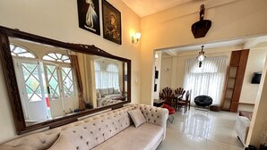 A living room with a large mirror, a sofa, a dining area with chairs and a table, and a hallway leading to another room. - MAPLES HOLIDAY RESORT (Nuwara Eliya)