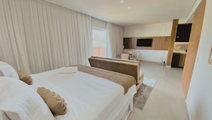 A modern hotel room with a large bed, a desk, and a TV. - Flat Ilê de Pipa Soé - By Almare (Tibau do Sul)