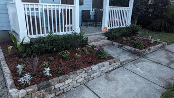 A residential property with a porch, two flower beds, and a mailbox.