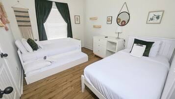 Een slaapkamer met een bed, een slaapbank, een bureau en een spiegel.