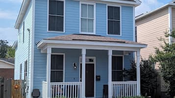 A two-story house with a front porch, a mailbox, and a small garden area.