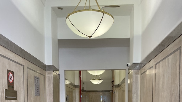 A hallway with a marble floor, a chandelier, and a red fire extinguisher. - Burne Jones By LFD (Birmingham)