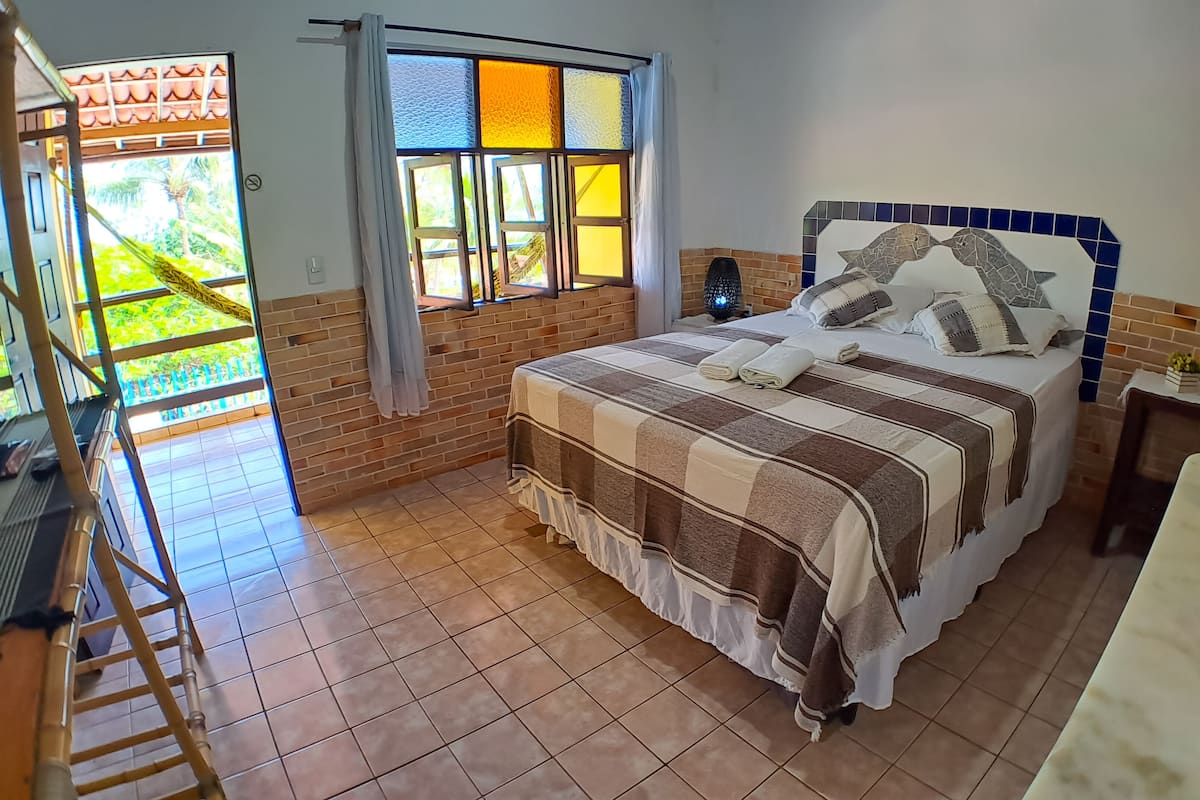 Une chambre à coucher avec un lit, une fenêtre, une table de chevet et une vue sur l’extérieur.
