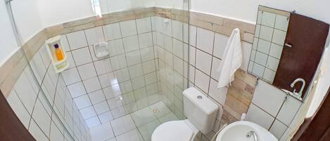 A bathroom with a toilet, sink, and glass shower enclosure.