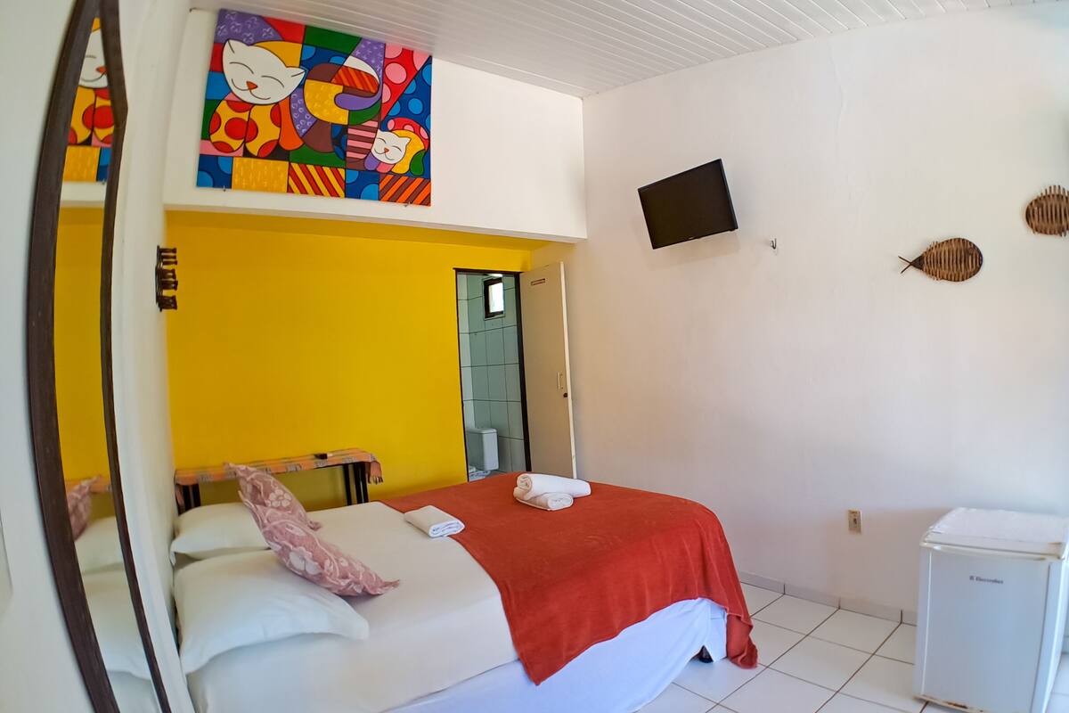 Une chambre d’hôtel avec un lit, une télévision et un petit réfrigérateur.