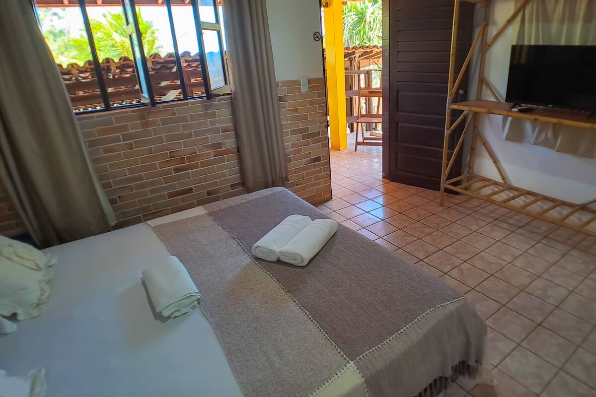 Une chambre d’hôtel avec un lit, un téléviseur posé sur un meuble et une vue sur l’extérieur.