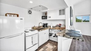 A modern kitchen with white cabinetry, a granite countertop, a built-in microwave, and a stove.