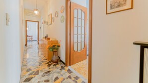 Un pasillo con piso estampado, una puerta de madera y cuadros en la pared.