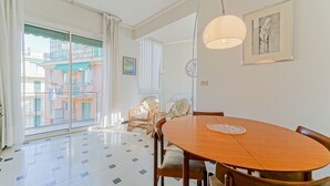 Un comedor amplio con una mesa y sillas de madera, un ventanal con vistas a edificios y una lámpara en el techo.