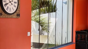 Een kamer met een groot raam, een klok aan de muur en een stoel.