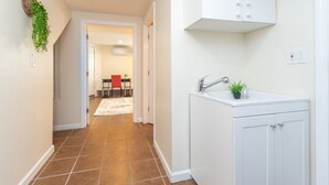 A hallway with a white cabinet, a sink, and a plant. - Cozy Boston Homestead : Sleeps 8, Pet Friendly (Framingham)