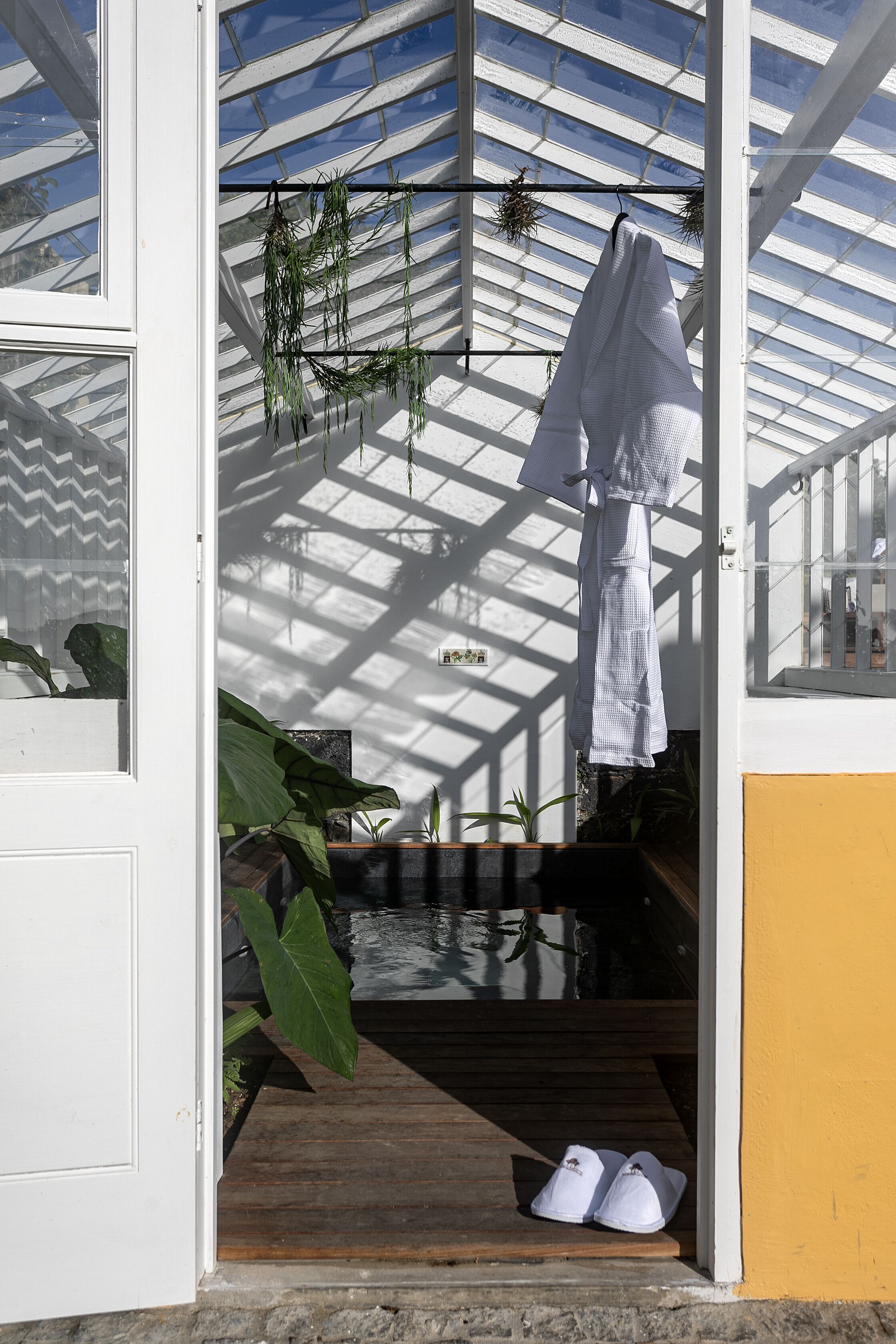 A covered porch with a wooden floor, a hanging white towel, and a pair of white shoes.