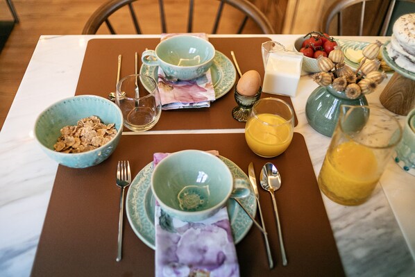 A breakfast table set with bowls, plates, cutlery, and a glass of orange juice. - Casa Portuguesa Charming House (Ponta Delgada)