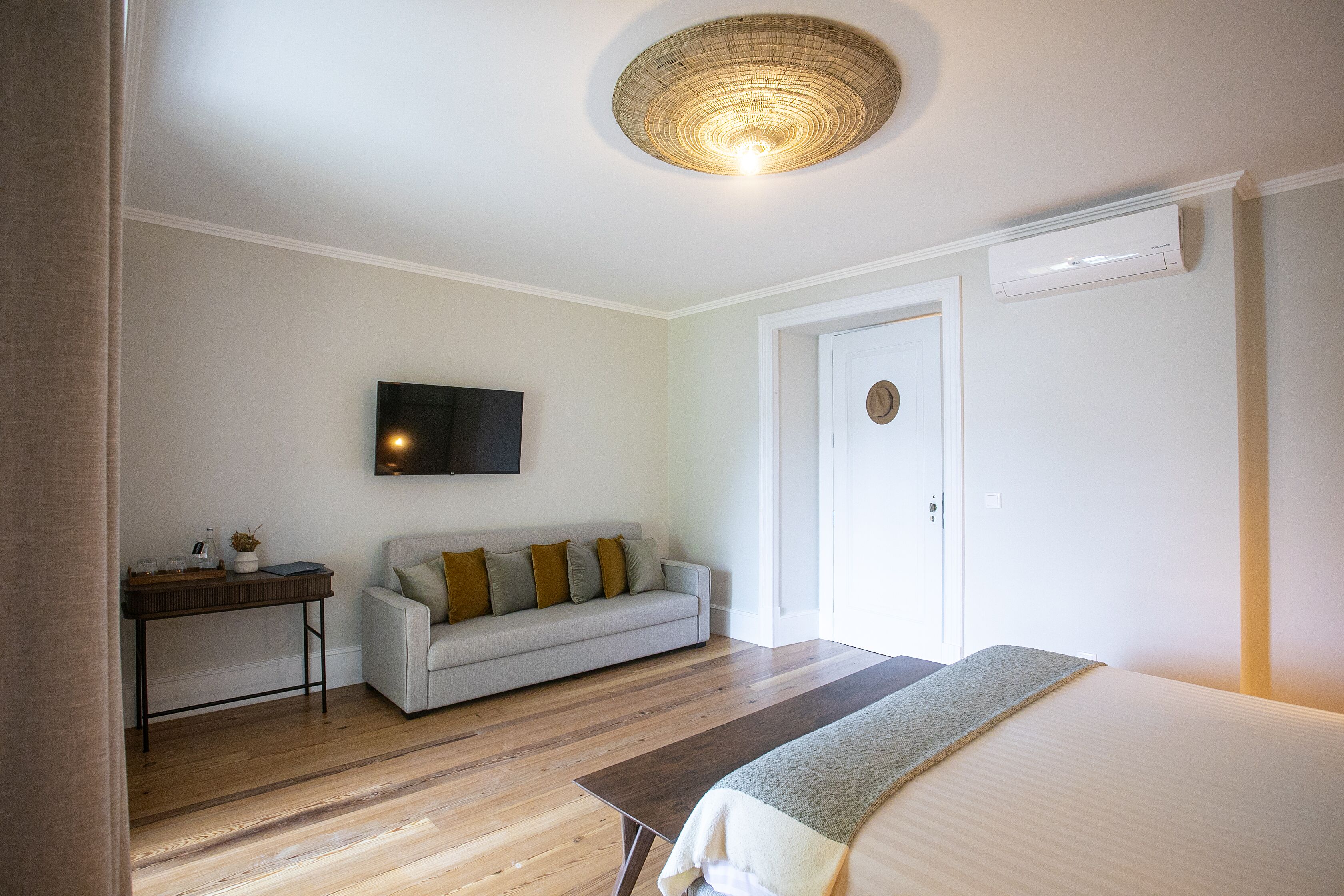 A modern bedroom with a bed, a sofa, a TV, and a ceiling light.