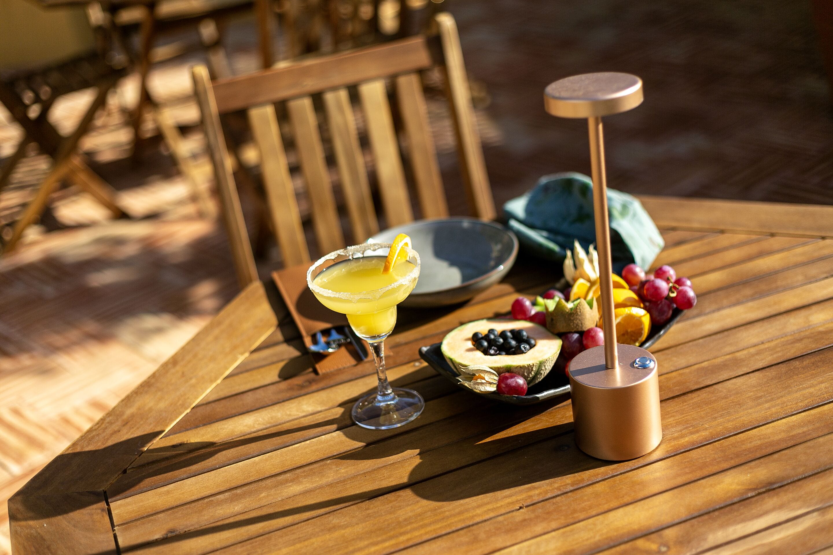 A wooden table with a drink, fruit, and a small device.