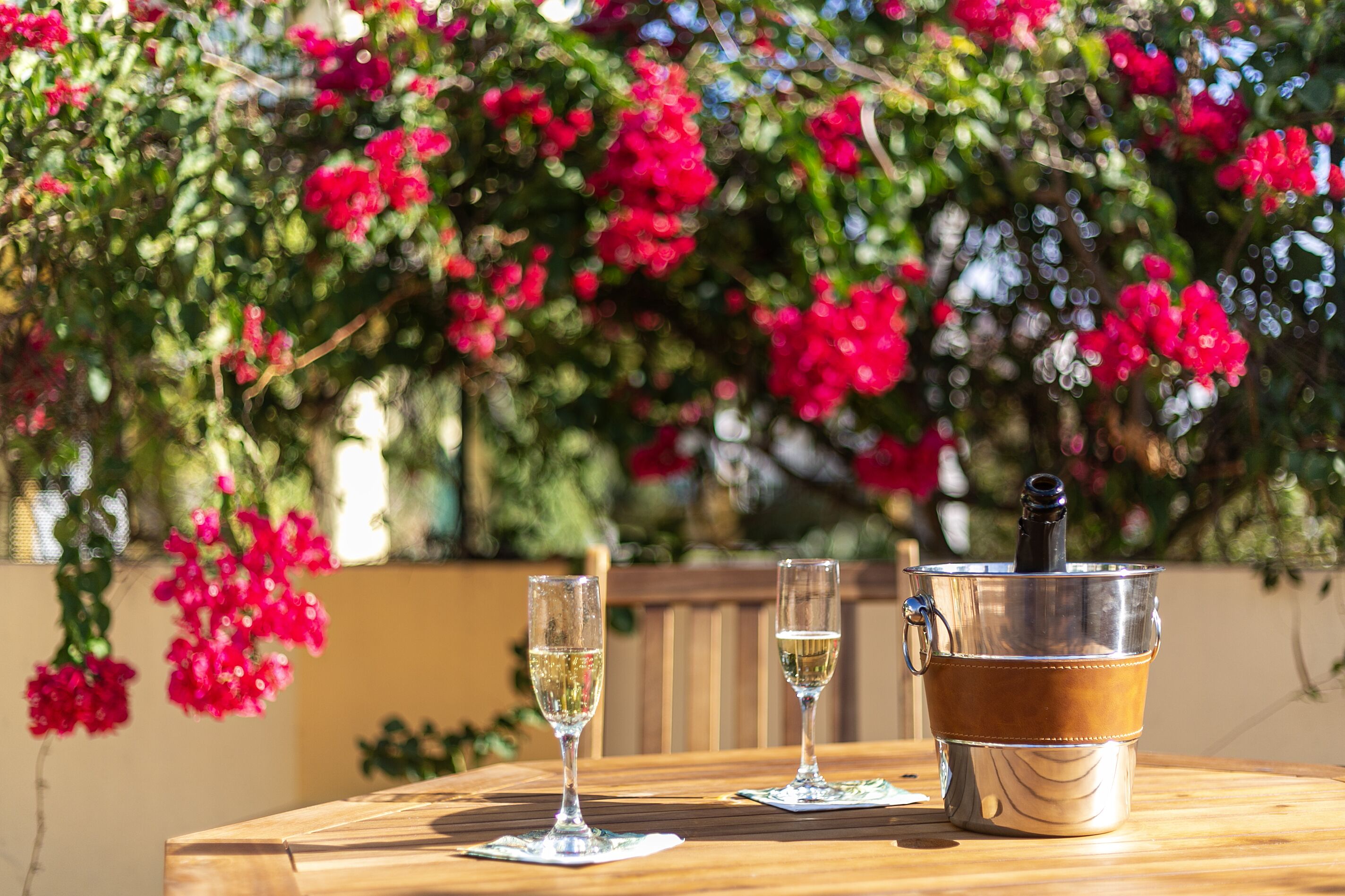 Une table en bois avec deux coupes de champagne et un seau en métal contenant une bouteille.