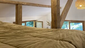 Un dormitorio con una cama grande, vigas de madera y una lámpara colgante.